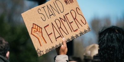 Photo of a protest sign which reads “Stand with Farmers”. Image by Gayatri Malhotra via Unsplash