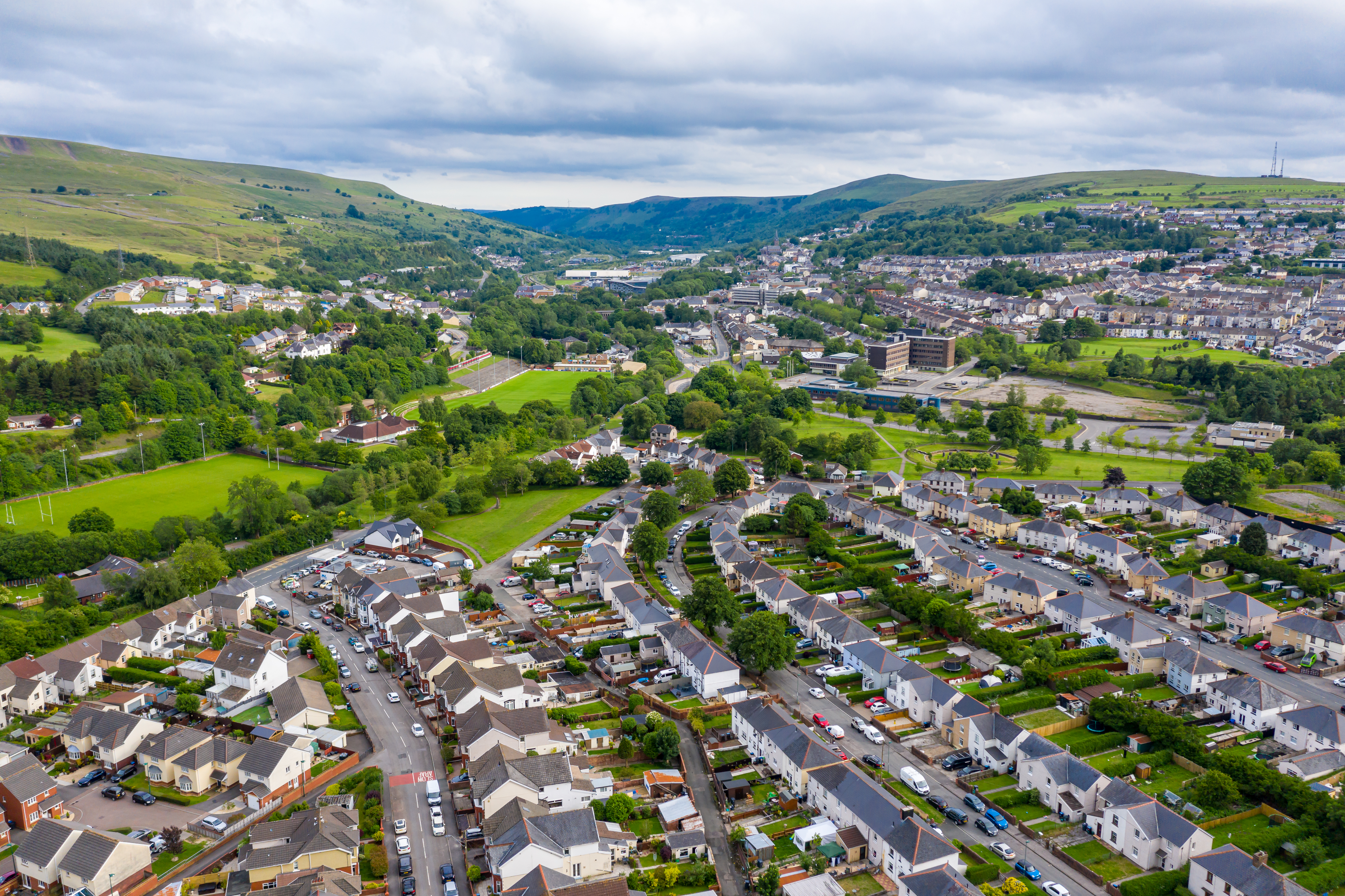 An aerial view of a neighborhood with green hills and agricultural lands in the distance. Photo by iStock.