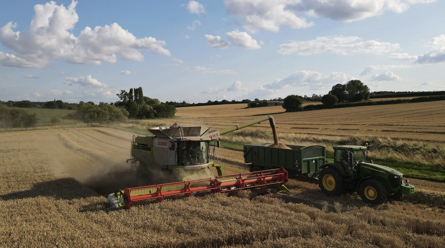 Combine harvester and tractor in field of wheat