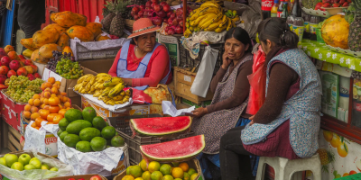 Three women sit at a market stall selling fruit in La Paz, Bolivia. Image credits: Lesly Derksen, Unsplash, Unsplash Licence.