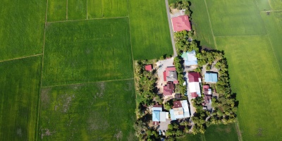 Alt text: Aerial image of green land parcel with small cottages amidst rice fields. Photo by Alor Setar via Pexels.