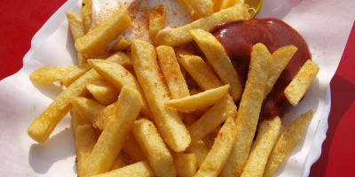 Photo of chips with ketchup and mayonnaise on white paper with red background. Photo by Marco Fischer via Pexels.