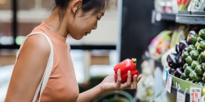  Image of a woman looking at vegetables in a supermarket aisle. Photo by Greta Hoffman via Pexels