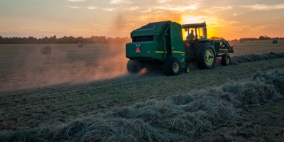 A tractor emitting fumes whilst ploughing a field. Photo by Jed Owen via Unsplash