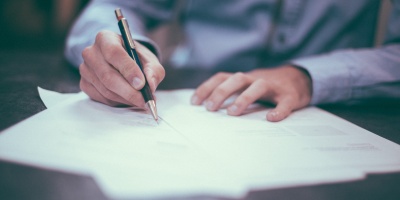 Photo of a man penning a letter. Photo by Scott Graham via Unsplash