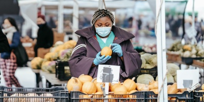 Photo of woman buying fruit with mask. Credit Laura James via Pexels. 