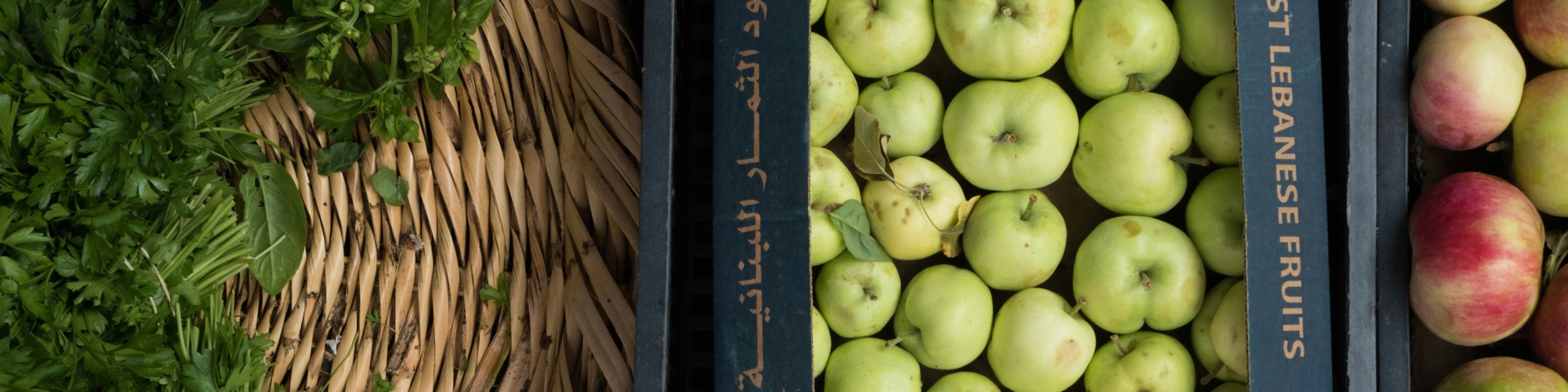 Baskets of apples and green leafy vegetables. Photo by Peter F via Unsplash.