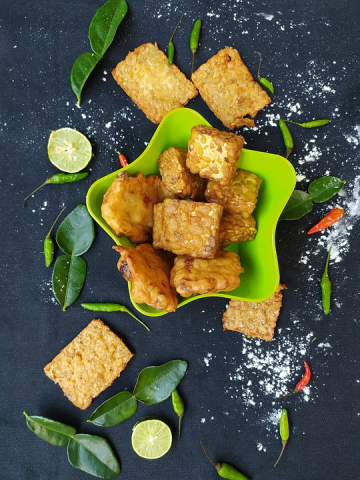 Cooked tempeh on a dish surrounded by chillies and slices of lime. Image credits: dyahahsina, Pixabay, Pixabay Licence.