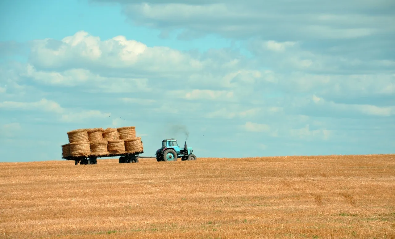 Image of a tractor collecting bales of hay. Photo by Gozha Net via Unsplash.