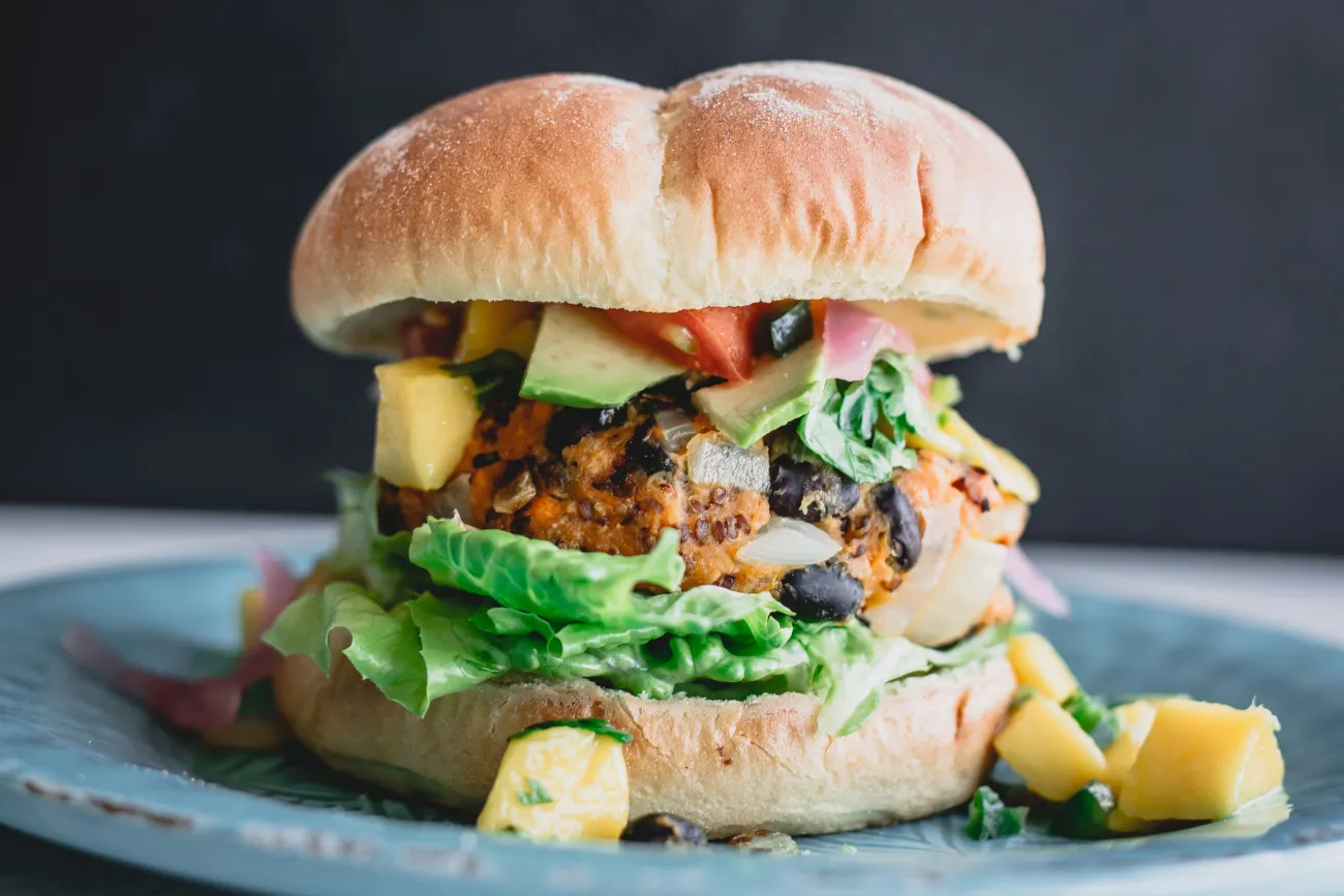 Image: image of a plant-based burger in front of a dark background. Photo by Deryn Macey via Unsplash