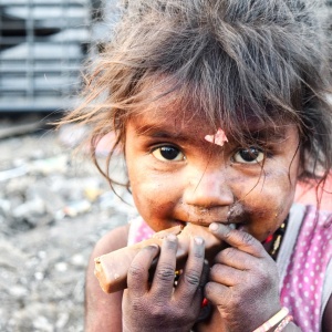 Image of an Indian child eating a chocolate bar. Photo by billycm via Pixaby