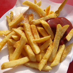 Photo of chips with ketchup and mayonnaise on white paper with red background. Photo by Marco Fischer via Pexels.