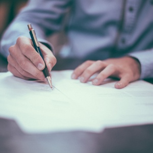 Photo of a man penning a letter. Photo by Scott Graham via Unsplash