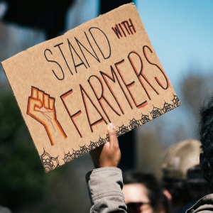 Photo of a protest sign which reads “Stand with Farmers”. Image by Gayatri Malhotra via Unsplash