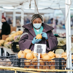 Photo of woman buying fruit with mask. Credit Laura James via Pexels. 